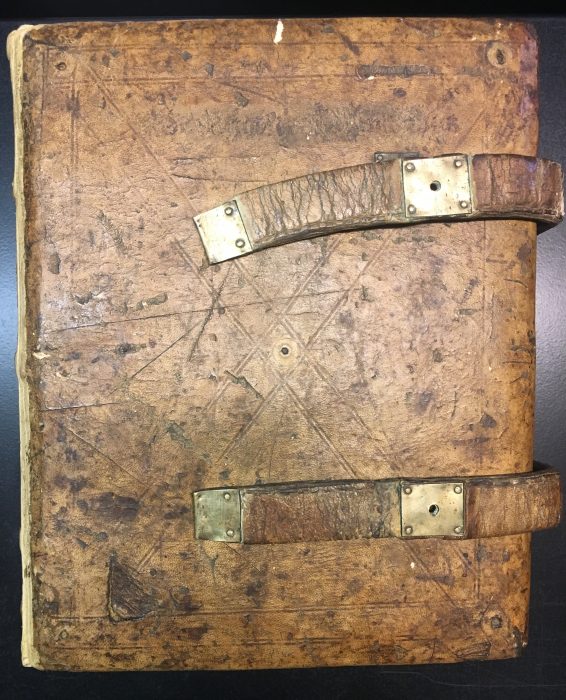 a photograph of the "Smaragdus manuscript," a brown leather-bound book, with metal clasps