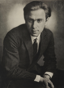 Image of a man in a pinstripe suit staring intently at the camera