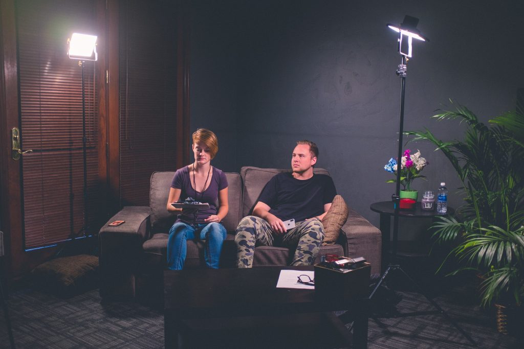 woman and man sitting under studio lights on sofa