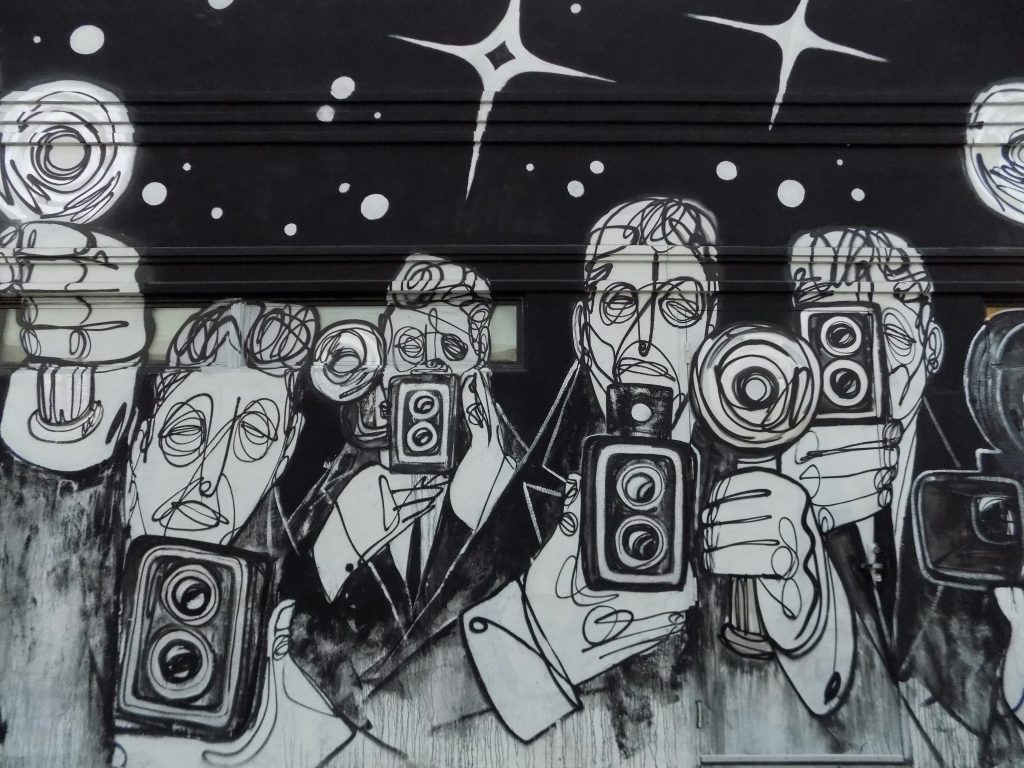wall graffiti in black and white of assorted men with cameras and flashes illustrated